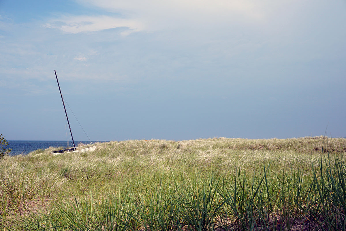 Free Grassy Dunes with Sailboat and Ocean View Stock Photography