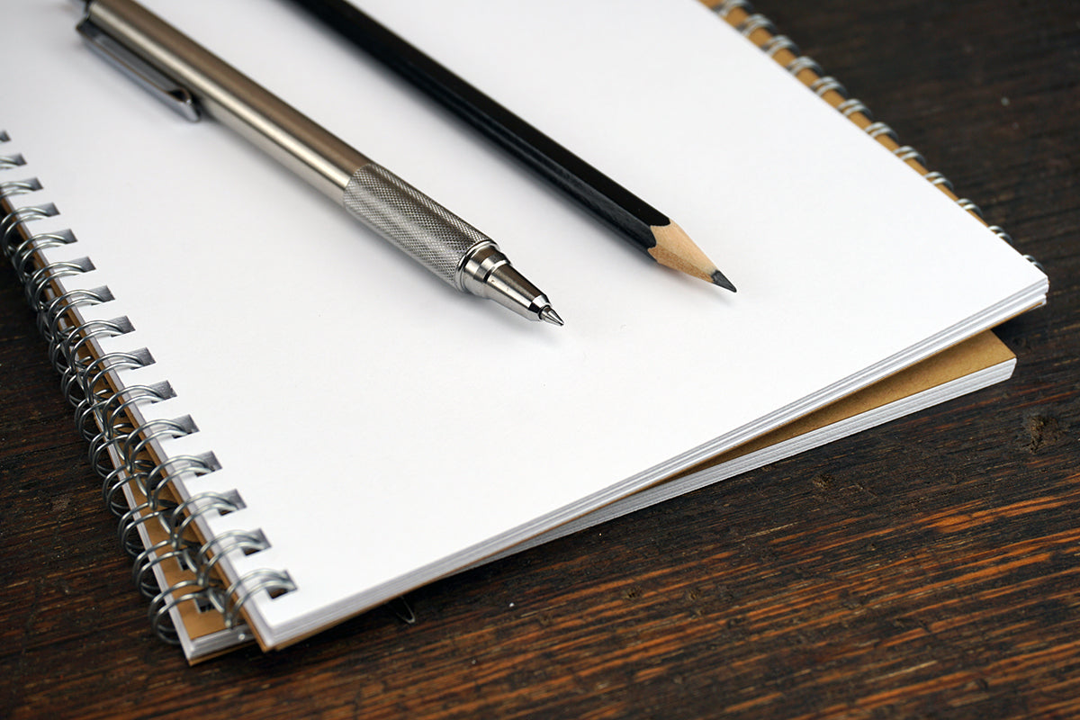 Free Pen and Pencil on White Notebook Stock Photography