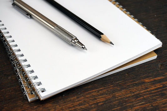 Free Pen and Pencil on White Notebook Stock Photography