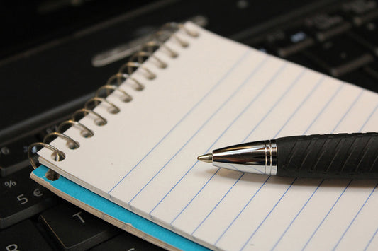 Free Pen and Notebook on Laptop Keyboard Stock Photography